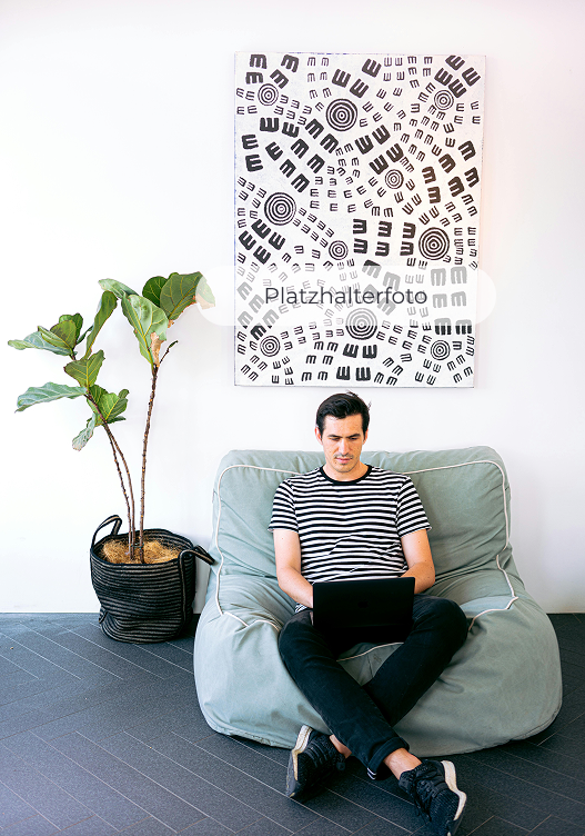 Programmer sitting on a sandbag next to a plant